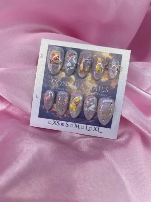 POOH (S);Short Almond - Unika handgjorda press-on naglar med lila, silverglittrig cateye bas och motiv inspirerade av Le Petit Prince. Kort-mandelformade och dekorerade med Nalle Puh o co., stjärnor och hjärtan. Perfekt för dig som vill ha något kreativt och färgglatt på naglarna.S: 15 mm, 11,5 mm, 12 mm, 11 mm, 9 mm 