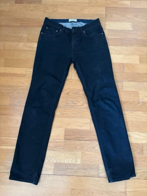 Svarta slim fit jeans från Acne Studios - Säljer ett par svarta slim fit jeans från Acne Studios. Klassisk femficksmodell med knappgylf och raka ben. Jeansen har en stilren look och är tillverkade i ett mjukt bomullsmaterial med lite stretch för extra komfort.