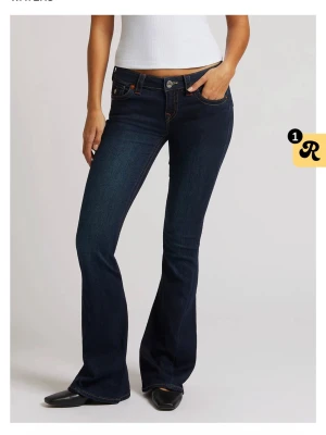 Mörkblå bootcut jeans True Religion low waist  - Som helt nya. Snygga mörkblå bootcut jeans från True Religion med klassiska kontrastsömmar och ikoniska fickdetaljer bak. Jeansen har låg midja och fem fickor, tillverkade i stretchigt denim för en bekväm passform. 