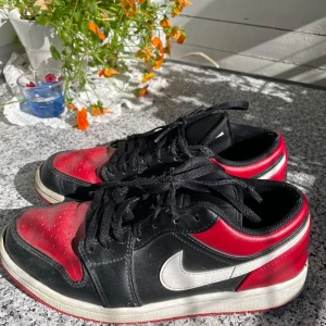 Nike Air Jordan 1 Low svart/röd - Snygga Nike Air Jordan 1 Low sneakers i svart och rött med vita detaljer. Storlek 41 och är i gott skick, men lite smutsiga. Är självklart öppen för prisförslag och säljer fler varor så köper du många får du också mängdrabatt. Obs säljes som på bild.