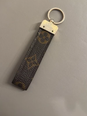 Louis Vuitton nyckelring  - Jättefin nyckelring som är gjord av läder från en äkta louis vuitton väska. Den är använd och kan synas på vissa ställen.