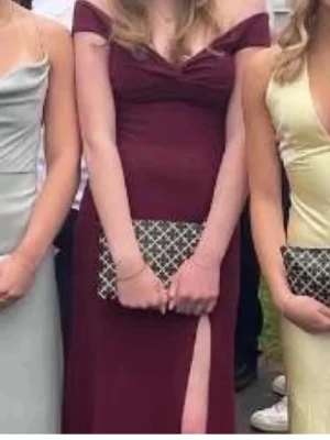 Balklänning!!!  - Vinröd långklänning med offshoulder och djup v-ringning. Klänningen har en hög slits framtill som ger en elegant look. Perfekt för bal eller festligare tillfällen. Materialet ser ut att vara mjukt och följsamt.