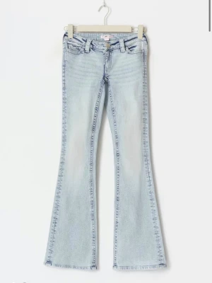 Ljusblå bootcut jeans med brodyr - Säljer ett par ljusblå bootcut jeans med utsvängda ben och snygg rosa brodyr på bakfickan. Ifrån Gina Young 14+, väldigt bra skick!!