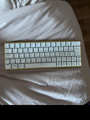 Kompakt vit mekanisk tangentbord - Snyggt kompakt mekaniskt tangentbord med vit färg på tangenterna och gul ram. Tangentbordet har en minimalistisk design utan numerisk del och passar perfekt för dig som vill ha mer plats på skrivbordet. Tangenterna är i plast och har tydliga symboler. Kostar ny 2000kr 