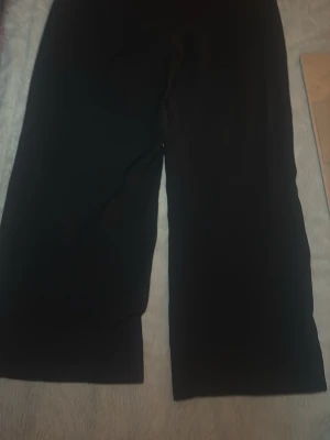 Svarta vida byxor med hög midja - Säljer ett par svarta byxor med breda ben och hög midja. Byxorna har en enkel och stilren design, perfekta för dig som gillar en avslappnad men trendig look. Materialet känns mjukt och följsamt, vilket gör dem sköna att bära hela dagen.