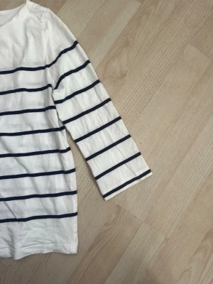 Randig vit topp med trekvartsärm - Vit topp med marinblå ränder och trekvartsärm. Använd endast några gånger, som nyskick. 