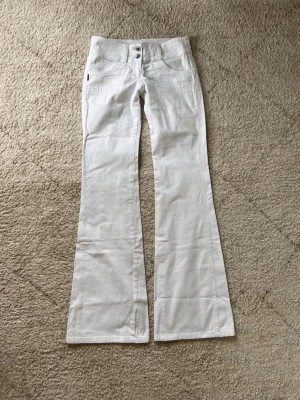 Vita lågmidjade utsvängda jeans - Supersnygga vita lågmidjade utsvängda jeans i mycket bra skick, inga defekter alls! Måtten finns bland bilderna, pris kan diskuteras🥰