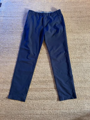 Mörkblå chinos från FootJoy - Mörkblå chinos från FootJoy med rak passform och klassisk design. Perfekta för en golfrunda. Knappt använda.