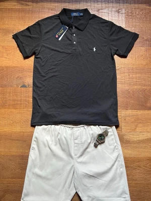 Ralph Lauren Piké Herr Small Svart  - Säljer en svart Polo Ralph Lauren piké i mycket fint skick. Klassisk och clean modell med vit logga på bröstet – passar till både vardag och mer uppstyrda outfits. Perfekt fit och enkel att matcha med shorts, jeans eller chinos.                                                 Kommer från ett rökfritt hem.                        Snabb leverans 📦                                              Bundledeals erbjuds