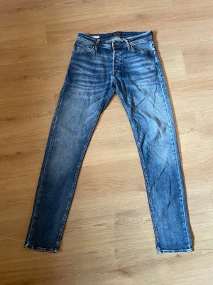 Jack & Jones jeans  - Snygga blå slim fit jeans med klassisk femficksdesign och lätt slitna detaljer framtill och baktill. Jeansen har normal midja och smala ben. Perfekta för en avslappnad och trendig look.                                                                                                            Pris kan diskuteras vid snabb affär.                                  Bara höra av sig vid frågor om vad som tex mått