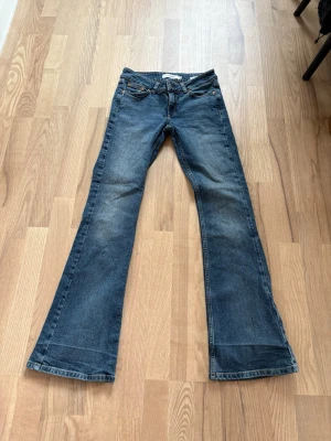 Blå utsvängda jeans från Junkyard - Säljer ett par blå utsvängda jeans från Junkyard i storlek XS. Jeansen har klassisk femficksdesign, normal midja och snygg tvätt med lätt slitningar. Perfekta för dig som gillar retrovibbar och vill ha ett par riktigt sköna jeans med mycket attityd. Men har väck där nere från att jag har vikt upp dom men går nog bort.