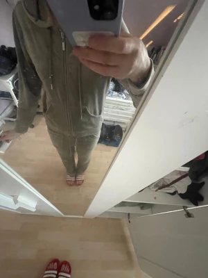 Grått mjukisset med dragkedja - Säljer ett grått mjukisset med zip hoodie och matchande byxor. Hoodien har fickor och dragsko i huvan, byxorna har resår i midjan. Perfekt för chill dagar hemma eller när du vill vara bekväm. Materialet känns mjukt och skönt mot huden.