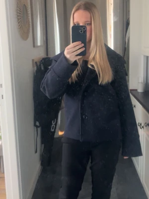 Mörkblå kappa från gina - Säljer en stilren mörkblå skepparkavaj med bred krage och knäppning framtill. Jackan har en klassisk rak passform och är perfekt för dig som gillar en tidlös look. Materialet känns kraftigt och passar bra till kyligare dagar.
