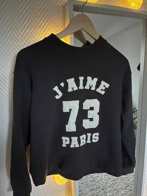 Mörkgrå sweatshirt från H&M - Mörkgrå sweatshirt från H&M med vit text på framsidan. Tröjan har rund halsringning, långa ärmar och är gjord i mjukt sweatshirtmaterial. Perfekt för en avslappnad och trendig look.