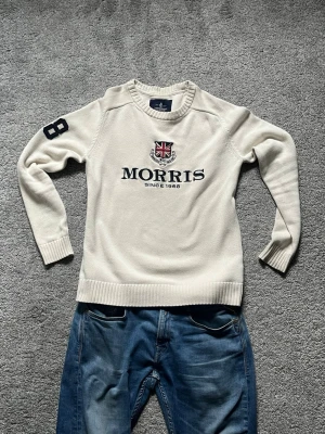 Vit stickad tröja från Morris - Snygg vit stickad tröja från Morris med broderad Union Jack och text på bröstet.  Storlek small, mycket bra skick!
