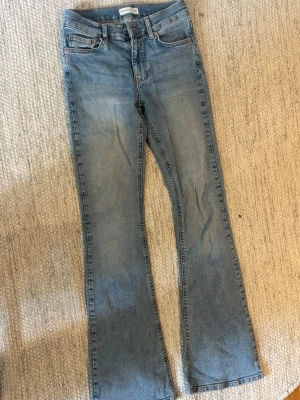 Ljusblå bootcut jeans från Gina Tricot - Säljer ett par ljusblå bootcut Perfect Jeans från Gina Tricot. Jeansen är midwaist och har utsvängda ben. Materialet är mjukt denim med lätt tvättad look och snygga sömmar. Perfekta för en avslappnad och trendig stil.