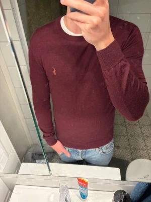 Vinröd stickad tröja Polo Ralph Lauren - Snygg vinröd stickad tröja från Polo Ralph Lauren i slim fit-modell. Tillverkad i mjuk och tvättbar merinoull. Kan gå ner i pris vid snabb affär! 