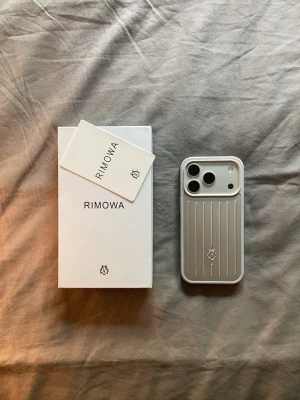 Silver mobilskal från Rimowa - Snyggt och stilrent mobilskal från Rimowa i silverfärg. Skalet har en räfflad design som påminner om Rimowas klassiska resväskor och är gjort i ett tåligt material. Perfekt för dig som vill ha ett exklusivt och modernt skydd till din mobil.