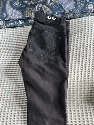 Svarta jeans från Dondup - Snygga svarta jeans från Dondup med klassisk femficksmodell och raka ben. Jeansen har en diskret logga på bakfickan och är tillverkade i ett mjukt denimtyg som sitter skönt. Perfekta för en stilren och avslappnad look.