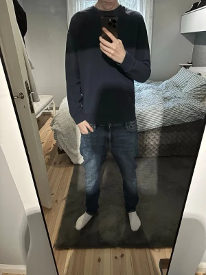 Mörkblå sweatshirt från peak performance  - En enkel och stilren mörkblå sweatshirt med rund hals och långa ärmar. Tröjan har en avslappnad passform och ribbade muddar vid ärmslut och nederkant. Perfekt att matcha med jeans eller joggers för en clean look.