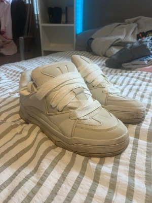 Bershka Vita chunky sneakers - Snygga vita sneakers med chunky design och bred sula. Skorna har tjocka vita skosnören och en vadderad plös för extra komfort. Tillverkade i syntetmaterial med en stilren look som passar till det mesta.