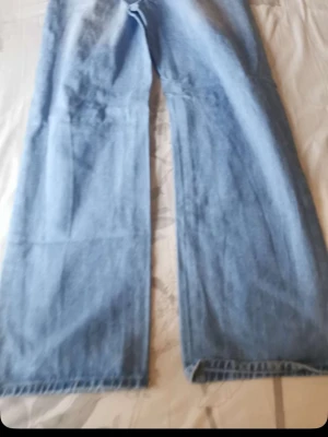 Ljusblåa wide leg jeans - Säljer ett par ljusblåa jeans med wide leg-passform. Jeansen har hög midja och raka, vida ben som ger en avslappnad och trendig look. Perfekta till sneakers eller boots. Klassisk denim i bomull.