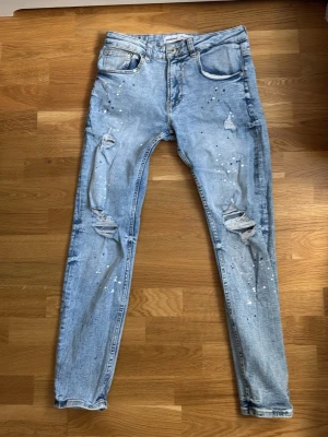 Bershka jeans  - Säljer dessa Bershka jeans med färg splash blå och vit på står ingen storlek men passar mig som har 28-31 i midjan och även längd 175.