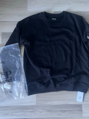 Svart sweatshirt - Snygg svart sweatshirt med klassisk rund halsringning och ribbade muddar vid ärmslut och nederkant. Tröjan är enkel och stilren, perfekt för dig som gillar minimalistisk design och streetwear-vibe. Materialet känns mjukt och bekvämt.