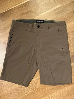 Bruna shorts från Sail Racing i strl S - Helt nya bruna chino shorts från Sail Racing med klassisk passform. De har två sidofickor med blixtlås, bälteshällor och knäppning fram. Materialet känns lätt och smidigt, perfekt för varma dagar. Bakfickor med knapp för extra stilpoäng. Resor innuti. Har ett pyttelitet hål av en säkerhetsnål som knapps syns vid vänster ficka.(se sista bilden)