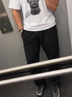 Vit t-shirt med Cristiano Ronaldos ansikte och Portugal  logga - Säljer en vit t-shirt med ett stort porträtttryck och signatur på framsidan samt en stor grafisk logga på ryggen. T-shirten har normal passform och korta ärmar, perfekt för dig som gillar statement-plagg och sportig stil.