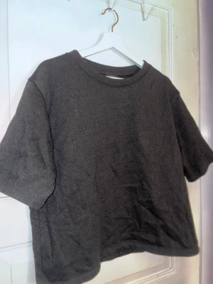 Svart glittrig t-shirt från Lindex - En svart glittrig oversized t-shirt från Lindex med rund halsringning och korta ärmar. Tillverkad i mjuk bomull som känns skön mot huden. Perfekt för en avslappnad och enkel stil.