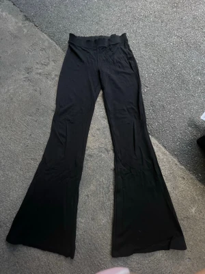 Svarta utsvängda leggings Gina Tricot - Svarta leggings från Gina Tricot med utsvängda ben och bred resår i midjan. Mjukt och stretchigt material som sitter skönt och följer kroppen. Perfekta till sneakers eller boots för en trendig look.