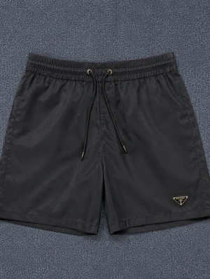 Prada badshorts - Två par stilrena shorts från Prada, ett par svarta och ett par vita. Båda har elastisk midja med snörning och den ikoniska Prada-loggan på benet. Tillverkade i ett glansigt syntetmaterial som ger en modern look. Perfekta för sommaren och enkel att matcha. Finns i M och L 