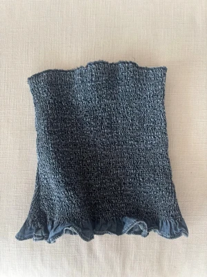 Mörkblå bandeau topp från Zara - Trendig mörkblå bandeau topp från Zara med smockad struktur och volangkant nedtill. Toppen är axelbandslös och har en croppad passform.