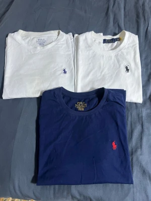 3-pack Polo Ralph Lauren t-shirts - Tre tröjor från polo Ralph Lauren. En vit med marinblå tryck. En vit med svart tryck och en marinblå med röd tryck. Den marinblåa tröjan är helt ny och oanvänd. Samma sak gäller den vit svarta. Vit blå tröjan är dock använd ett antal gånger och vänligen obs att det kan finnas täcken på att den är använd l. Alla är i storlek S förutom vit svarta vilket är storlek M.