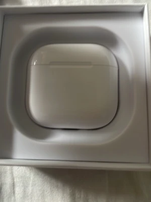 Apple AirPods med laddningsetui - Säljer ett par vita Apple AirPods med laddningsetui. Snygg och stilren design i blank plast, perfekt för dig som vill ha trådlösa hörlurar med grym ljudkvalitet och enkel anslutning till iPhone eller andra Apple-enheter.