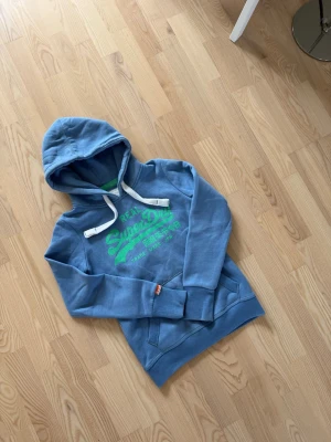 Superdry hoodie - Säljer en riktigt fet superdry hoodie i storlek S. Den är helt utan skavanker och i jätte bra skick näst intill nytt. Då den bara har blivit använd runt 3 gånger. Vid frågor om bilder eller liknande så är det bara att fråga😊💛