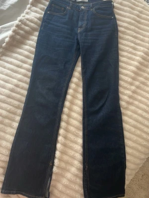 Mörkblå bootcut jeans med slits - Snygga mörkblå bootcut jeans från MANGO med slits längst ner på benen och kontrastsömmar. Jeansen har klassisk mörkblå färg. Modellen heter Elle. Säljs pga blivit för små. Storlek 36!