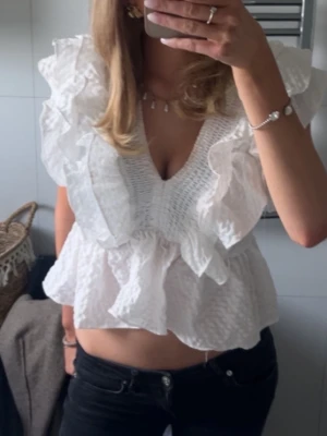 Vit volangblus med v-ringning - Säljer en superfin vit blus med djup v-ringning och stora volangdetaljer. Knappt använd❤️