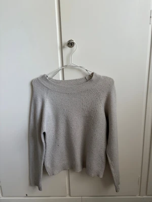 Beige stickad tröja Vero Moda - Mysig beige stickad tröja från Vero Moda med rund halsringning och långa ärmar. Tröjan har ribbstickade muddar vid hals, ärmslut och nederkant. Enkel och stilren design som passar till det mesta.