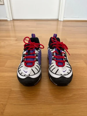 Nike Air Max 98 Raptors sneakers - Storlek 40 - Säljer ett par Nike Air Max 98 Raptors i storlek EU 40 . Klassisk och väldigt populär färgställning i vitt, svart, lila och rött som ger en riktigt snygg streetwear-look och funkar till det mesta. Skorna är i bra begagnat skick med normalt slitage från användning. De är rengjorda och redo att användas direkt. Sitter skönt på foten och har den ikoniska Air Max-dämpningen som gör dem bekväma även vid längre användning.