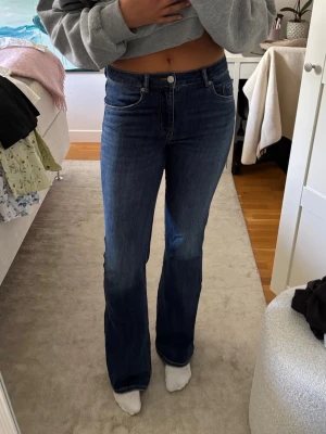 Mörkblå bootcut jeans - Säljer ett par mörkblå bootcut jeans i tall med medelhög midja och klassisk femficksdesign. Jeansen har en snygg tvätt och är tillverkade i stretchigt denimtyg för skön passform. Perfekta till en avslappnad look och passar till det mesta.