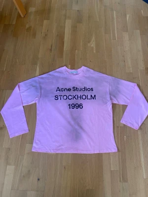 Acne studios Rosa tröja  - Acne Studios Stockholm 1996 Longsleeve – Toppskick  Stilren och eftertraktad longsleeve från Acne Studios i en snygg ljusrosa färg med ikoniskt “Stockholm 1996”-tryck framtill. Tröjan är i toppskick, mycket sparsamt använd och utan fläckar, hål eller andra anmärkningar.  ✨ Klassisk Acne Studios-design ✨ Mjuk och bekväm passform ✨ Ljusrosa färg som sticker ut på ett stilrent sätt ✨ Perfekt till både vardag och mer uppklädda outfits  Skick: 10/10 Färg: Rosa Märke: Acne Studios 