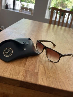 Ray-Ban boyfriend solglasögon leopard färg - Snygga solglasögon från Ray-Ban med bruna bågar i plast och tonade glas. Klassisk fyrkantig form och diskret Ray-Ban-logga på sidan. Kommer med originalfodral. Perfekta för soliga dagar och ger en cool vibe.