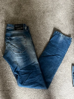 Nya Blå jeans från replay i storlek (W30-L34) - Säljer ett par blå jeans från replay med snygg klassisk femficksdesign. Jeansen har raka ben och är tillverkade i denim med cool faded effekt. Perfekt för dig som gillar en avslappnad och trendig look.
