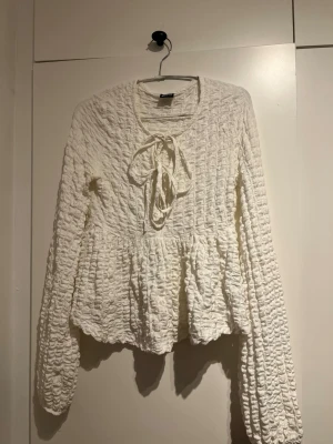 Vit fin blus med knyt från gina  - Superfin vit blus med lång ärm och volang nedtill. Blusen har en strukturerad, nästan krinklad yta och knytband vid halsen. Från gina Tricot storlek S🩷 i mycket bra skick!