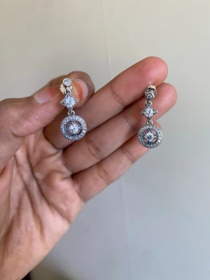 Pandora Silvriga örhängen med gnistrande stenar - Snygga silvriga örhängen med hängande design. Örhängena har runda och fyrkantiga former med glittrande stenar i mitten och små detaljer runt om. Perfekta för att ge din look lite extra bling.material sterling silver