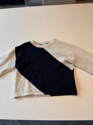 Stickad tröja Gina Tricot svart/vit storlek 146-152 - Säljer en snygg stickad tröja från Gina Tricot i mörk blå och vit med coolt diagonal färgblocksmönster. Tröjan har rund halsringning och långa ärmar. Perfekt för dig som gillar en trendig och bekväm stil.