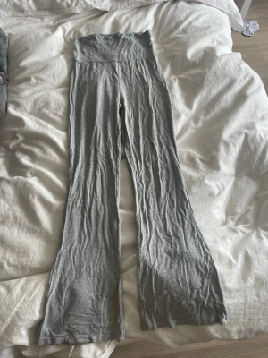 Grå ribbade bootcut leggings - Snygga grå leggings med ribbad struktur och bootcut-ben. Hög midja för extra komfort och trendig look. Perfekta till en avslappnad outfit eller när du vill vara bekväm men ändå se stilsäker ut. Mjukt och stretchigt material.