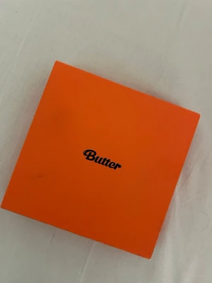 BTS Butter Album Peach Version  - Säljer min BTS album Butter peach version. Fick den som present ett tag sen när min intress för K-Pop minskade. Den är helt oanvänd, precis som ny dock är själva ”lådan” lite skadad. Albumet innehåller en photocard, en postcard, en ”special message” från en av medlemmarna, photo album och en skiva. 